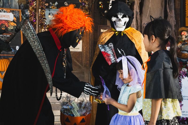 ハロウィンマンとお菓子をもらう子どもたち