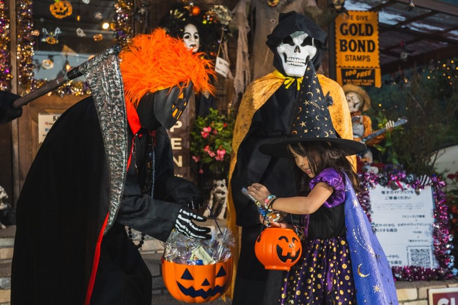 ハロウィンマンからお菓子をもらう魔女の仮装の女の子