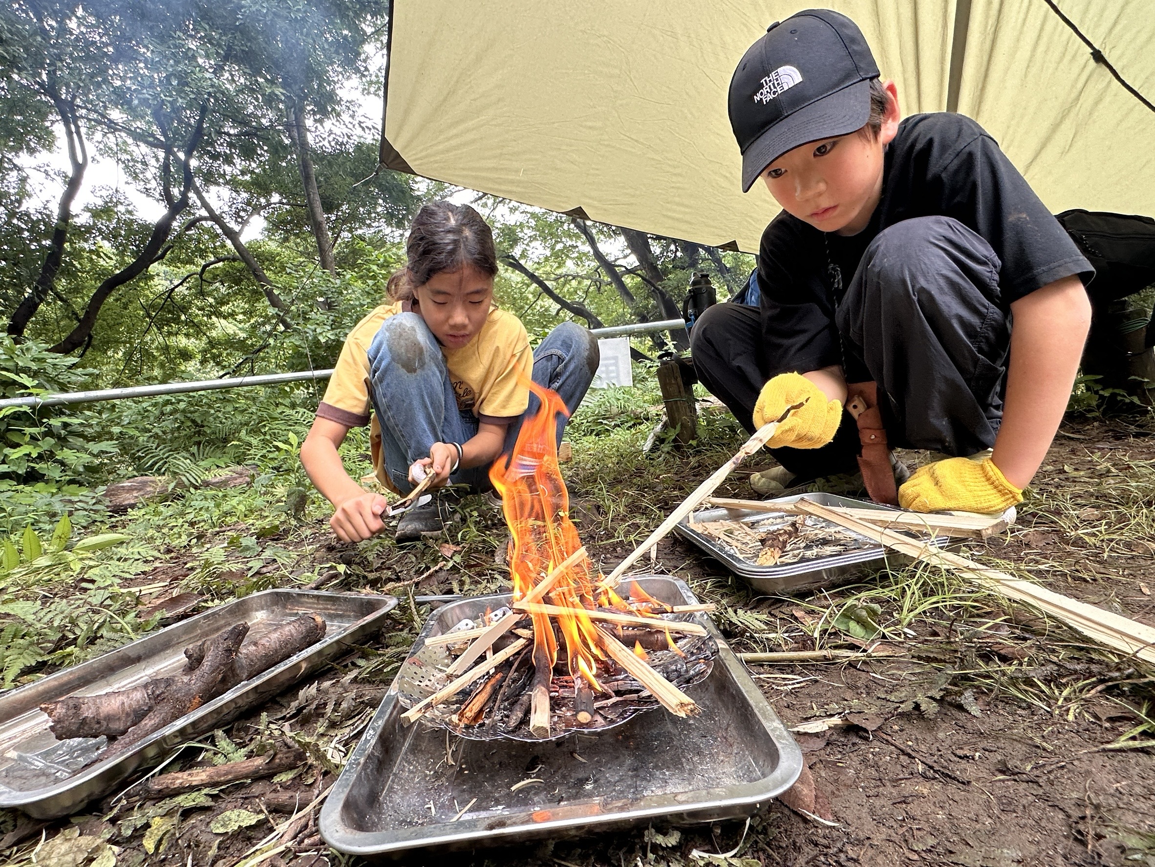 自然の中で火起こしに挑戦する子どもたち